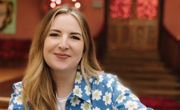 Abbie McCarthy poses in a blue jacket with daisy print