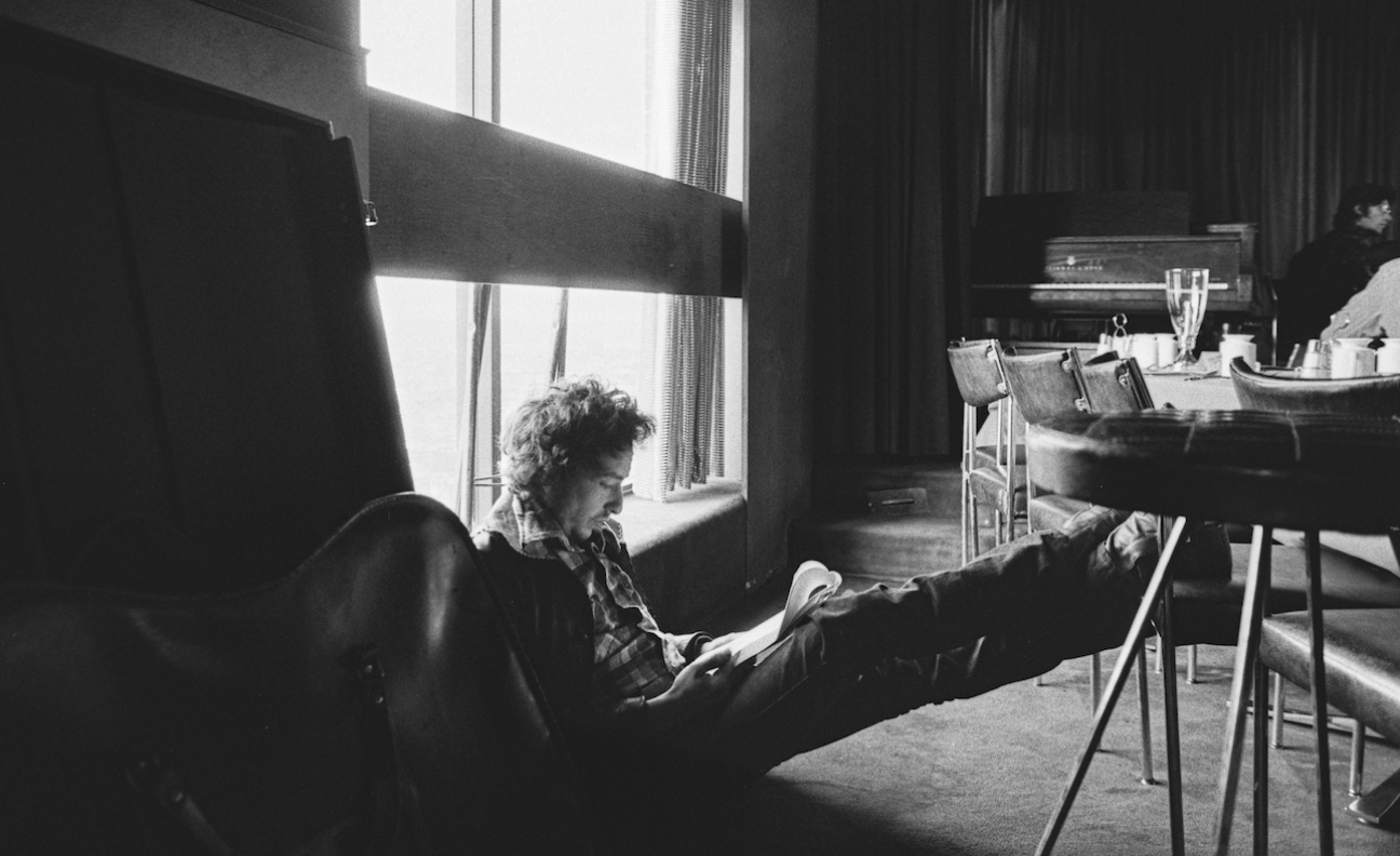 Bob Dylan sat on floor writing notes, shot in black-and-white in 1974