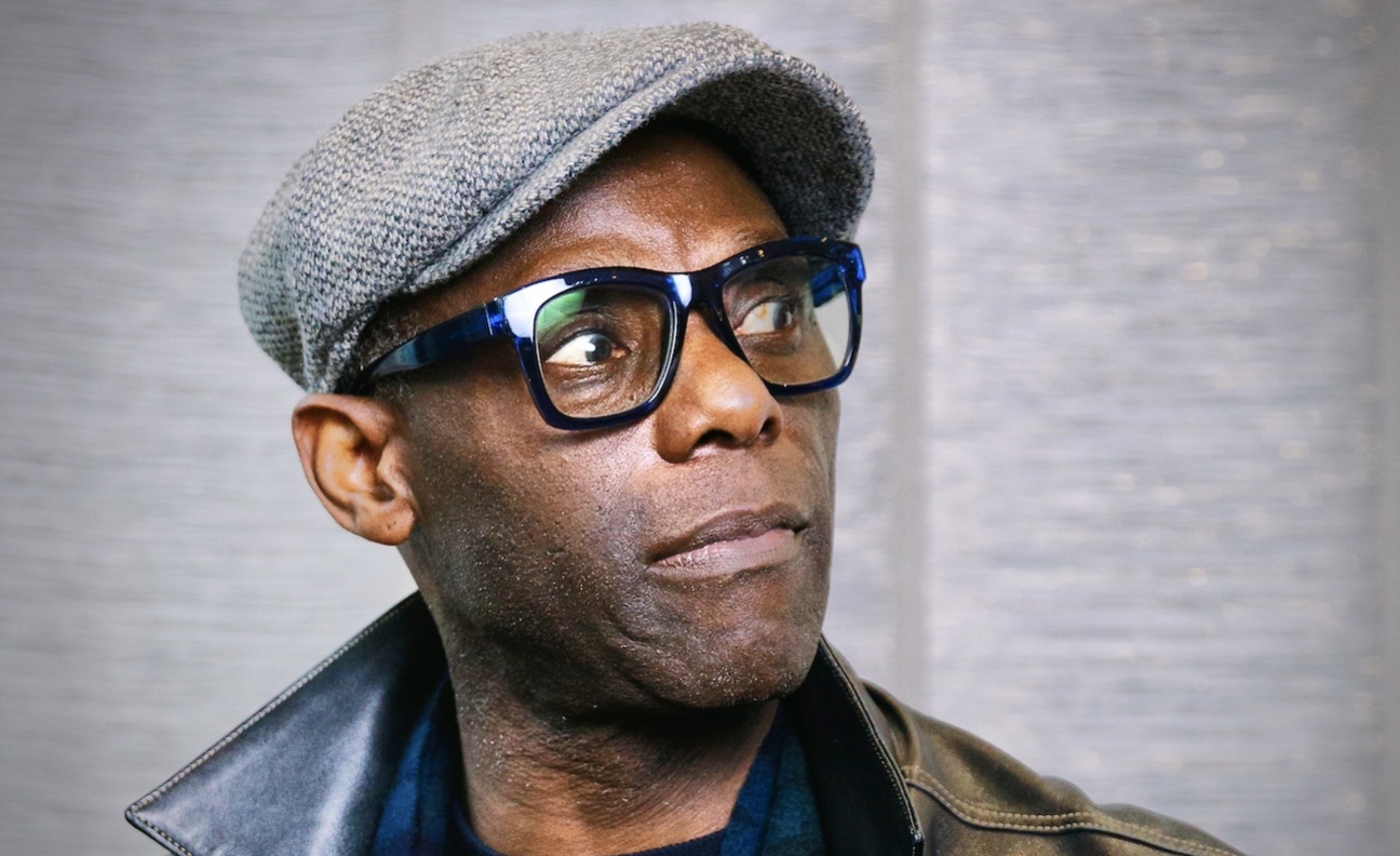 Mykaell Riley poses in a grey flatcap