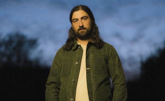 Noah Kahan poses in a dark green jacket