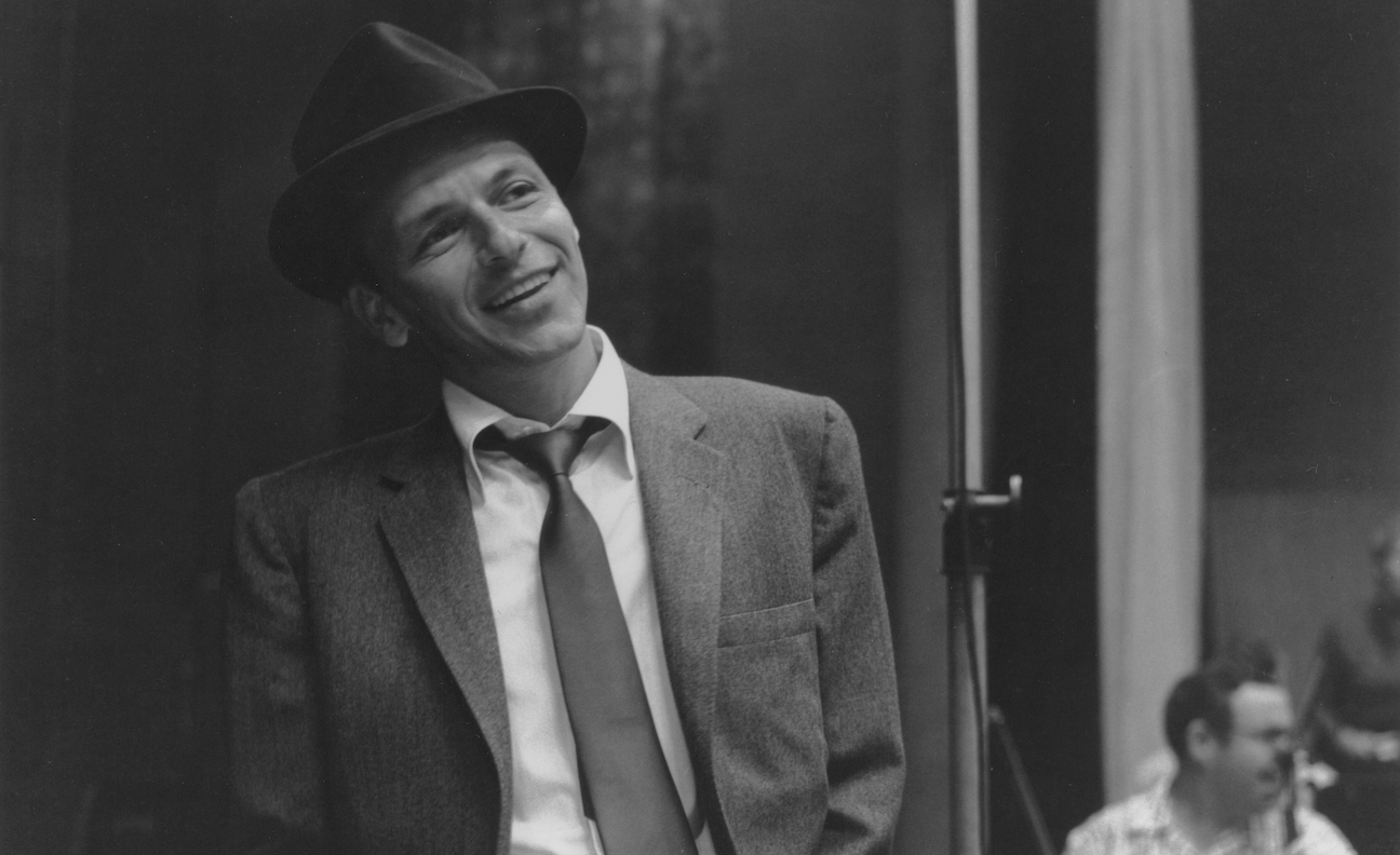 Frank Sinatra wears a hat and poses in a black and white image