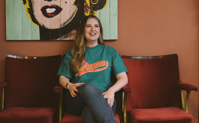 Abbie McCarthy sits on a chair with a pop art print of Marilyn Monroe behind her